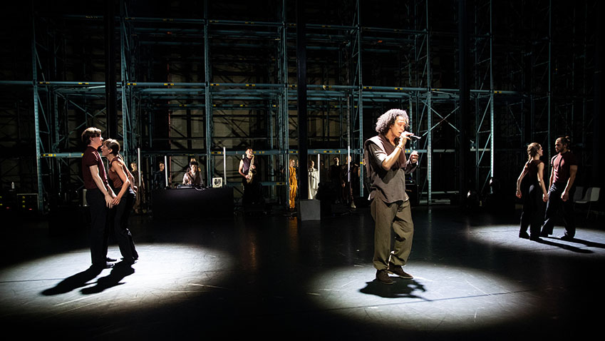 DOX in het midden in een spotlight, met links en rechts dan hem elk twee dansers die ook in spotlichten staan