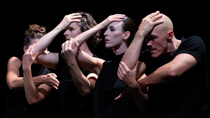 Drie dansers met hand tegen het voorhoofd, met de andere armen en handen aan elkaar verbonden