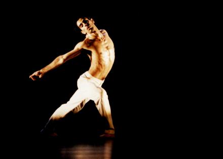 Beeld van een danser in witte broek met ontbloot bovenlijf uit Le Sacre du Printemps - Choreografie Ed Wubbe